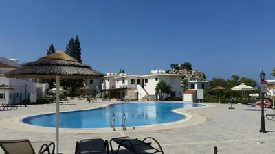 a large swimming pool with chairs and an umbrella at STAY Monte Elias Apartment in Protaras
