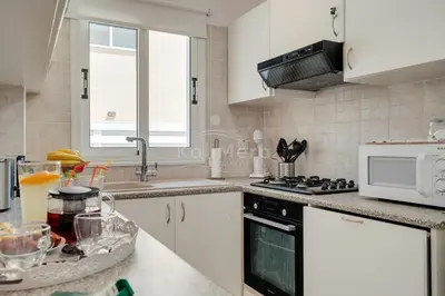 a kitchen with white cabinets and a sink and a microwave at Villa Maddie in Protaras