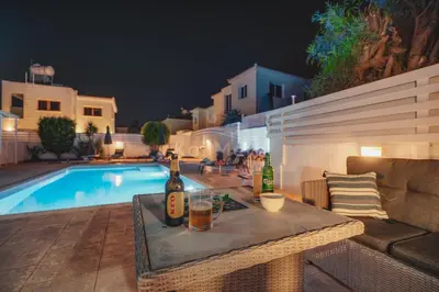 a table with bottles and drinks on it next to a pool at Villa Maddie in Protaras