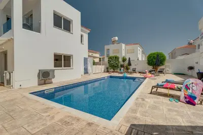 a swimming pool in a villa with a house at Villa Maddie in Protaras