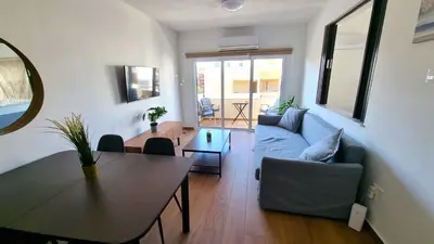 a living room with a table and a blue couch at Sea View Apt - 2 min walk to the Beach & 200 Mbit Highspeed internet in Larnaka