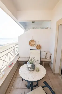 a table and chairs on a balcony with the beach at Quattro Beachfront Sea View Ap 4 in Larnaka