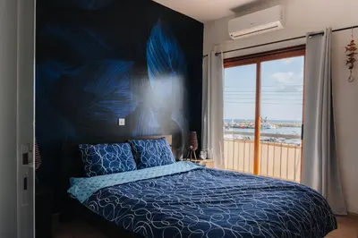 a bedroom with a blue bed and a large window at Zima Two Seaside in Zygi