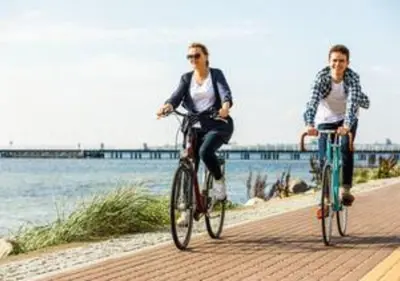 two people riding bikes on a sidewalk near the water at Zima Two Seaside in Zygi