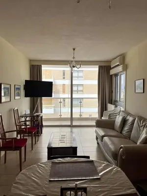 a living room with a couch and a large window at Beach apartment Mackenzie, Larnaca in Larnaka