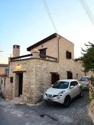 a white car parked in front of a brick building at Symela's Nest in Anoyira
