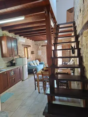 a kitchen and dining room with a wooden spiral staircase at Symela's Nest in Anoyira