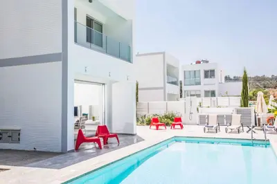 a villa with a swimming pool and red chairs at Protaras Greco Villa CCV1 in Protaras