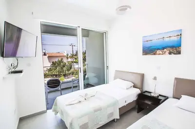 a white bedroom with two beds and a balcony at Protaras Greco Villa CCV1 in Protaras