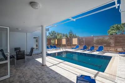 a swimming pool in a house with chairs around it at Napa Nissi House in Ayia Napa