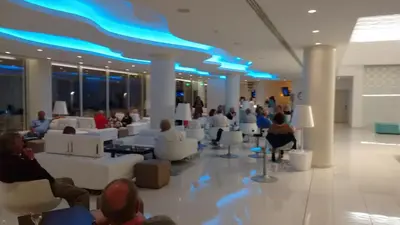 a group of people sitting in a lobby with white couches at Vrissaki Beach Hotel in Protaras