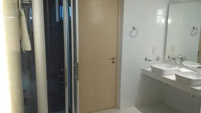 a bathroom with two sinks and a glass shower door at Vrissaki Beach Hotel in Protaras