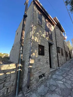 an old stone building with a long pipe on it at Lofou Maisonette in Lofou