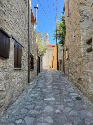 an alley with stone buildings and a tower at Lofou Maisonette in Lofou