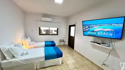 a hotel room with two beds and a flat screen tv at Napa Gem in Ayia Napa