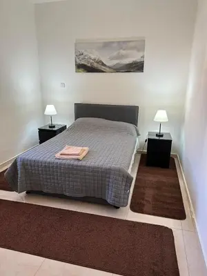 a bedroom with a bed with two nightstands and two lamps at Chariandry Residence, Limassol City Centre in Limassol