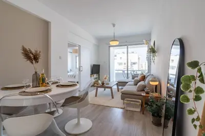 a white living room with a table and a couch at Hermes 2-Bedroom Apartment in Larnaca in Larnaka