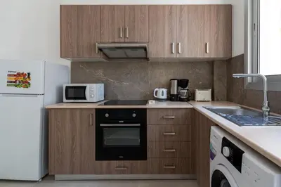 a kitchen with wooden cabinets and a white refrigerator at Hermes 2-Bedroom Apartment in Larnaca in Larnaka
