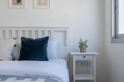 a bedroom with a bed with a blue pillow and a table at Hermes 2-Bedroom Apartment in Larnaca in Larnaka