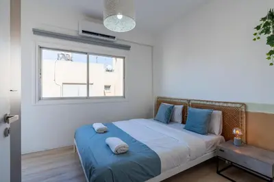 a bedroom with a bed with blue pillows and a window at Citrus 3-Bedroom Apartment in Larnaca in Larnaka