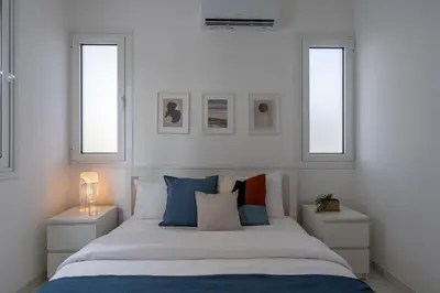 a bedroom with a large bed with two windows at Artemis 1-Bedroom Apartment in Larnaca in Larnaka
