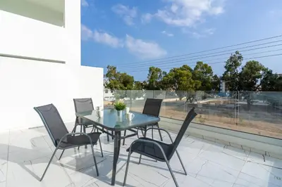 a glass table and chairs on a patio with a window at Artemis 1-Bedroom Apartment in Larnaca in Larnaka