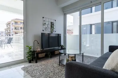 a living room with a tv and a couch and a table at Artemis 1-Bedroom Apartment in Larnaca in Larnaka