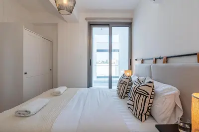 a white bedroom with a large white bed with pillows at Vanilla's Prime 1-Bedroom Apartment in Larnaca in Larnaka