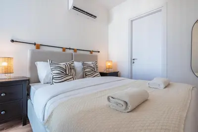 a white bedroom with a large bed with towels on it at Vanilla's Prime 1-Bedroom Apartment in Larnaca in Larnaka