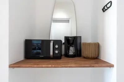 a microwave and a coffee maker on a wooden shelf at Latte's Prime 1-Bedroom Apartment in Larnaca in Larnaka