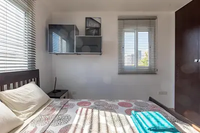 a bedroom with a bed and two windows at Cosy Apart at Lykavitos in Nicosia