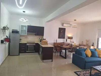 a kitchen and living room with a table and a blue couch at Paramount Gardens Resorts D204 in Tersephanou