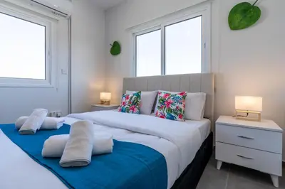 two beds in a bedroom with two windows at Diamond’s 2-Bedroom Apartment in Larnaca in Larnaka