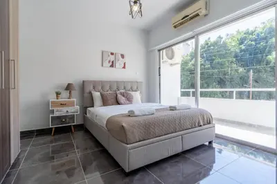 a bedroom with a bed and a large window at Powder’s 1-Bedroom Retreat in Mackenzy, Larnaca in Larnaka