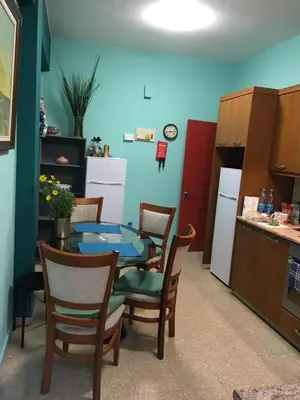 a kitchen with a table and chairs and a kitchen with a refrigerator at Past or Tail hostel in Larnaka
