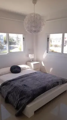 a white bedroom with a large bed and two windows at Welcome to Thea Court in Paralimni