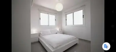 a white room with a bed and two windows at Welcome to Thea Court in Paralimni