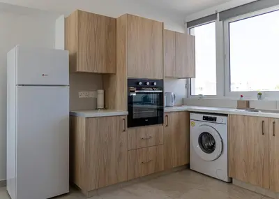 a kitchen with wooden cabinets and a white refrigerator at Larnaca BeachHouse in Larnaka
