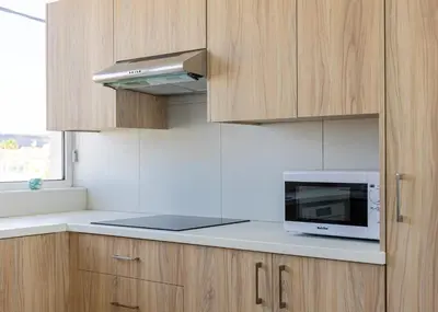 a kitchen with a microwave oven and wooden cabinets at Larnaca BeachHouse in Larnaka