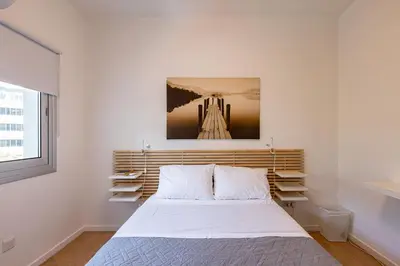 a white bedroom with a bed and a window at City Center Apartment in Nicosia