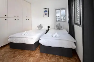 two beds in a bedroom with white walls and wooden floors at Urban Condo 10 - 2 Bdr in Nicosia