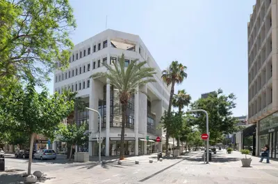 a large white building on a street with palm trees at Urban Condo 10 - 2 Bdr in Nicosia