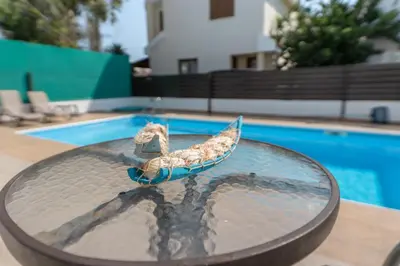 a toy boat sitting on a table next to a swimming pool at Sun & Sand Private Villa in Protaras