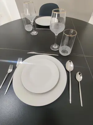 a black table with white plates and silverware on it at Maestro I Apartment in Larnaka