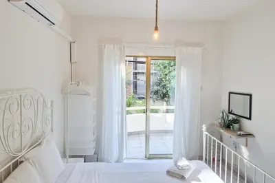a white bedroom with a bed and a sliding glass door at Palmove Makenzie Studio 4 in Larnaka