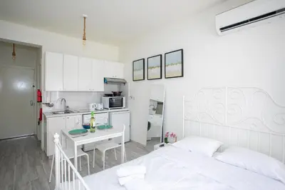 a white bedroom with a bed and a kitchen at Palmove Makenzie Studio 4 in Larnaka