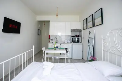 a bedroom with a white bed and a kitchen at Palmove Makenzie Studio 4 in Larnaka
