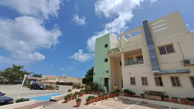 a green and white building with a parking lot at Dream Beach House Steps from the Sea & Free Parking in Protaras