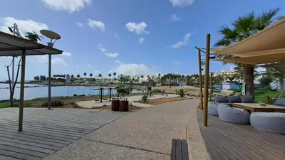 a patio with tables and benches and a view of the water at Dream Beach House Steps from the Sea & Free Parking in Protaras
