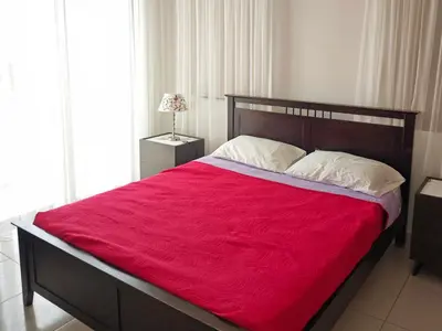 a bedroom with a large bed with a red blanket at Fotini Villas in Protaras